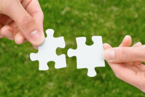 Zwei Hände halten zwei Puzzlestücke aneinander