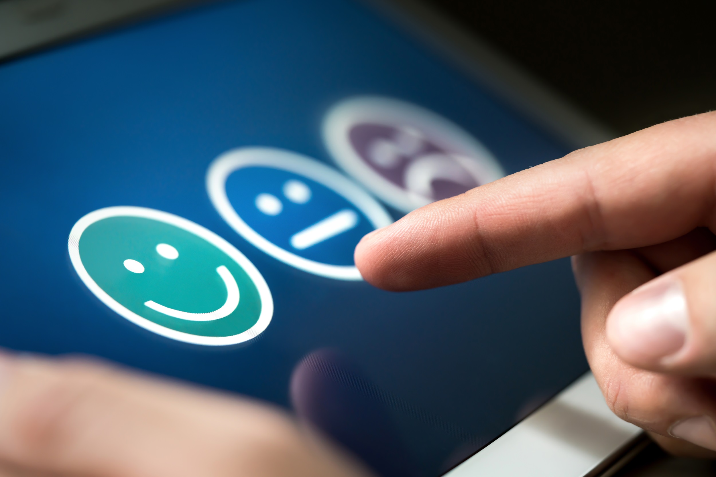 Umfrage mit drei Smilies zur Zufriedenheit angezeigt auf einem Tablet