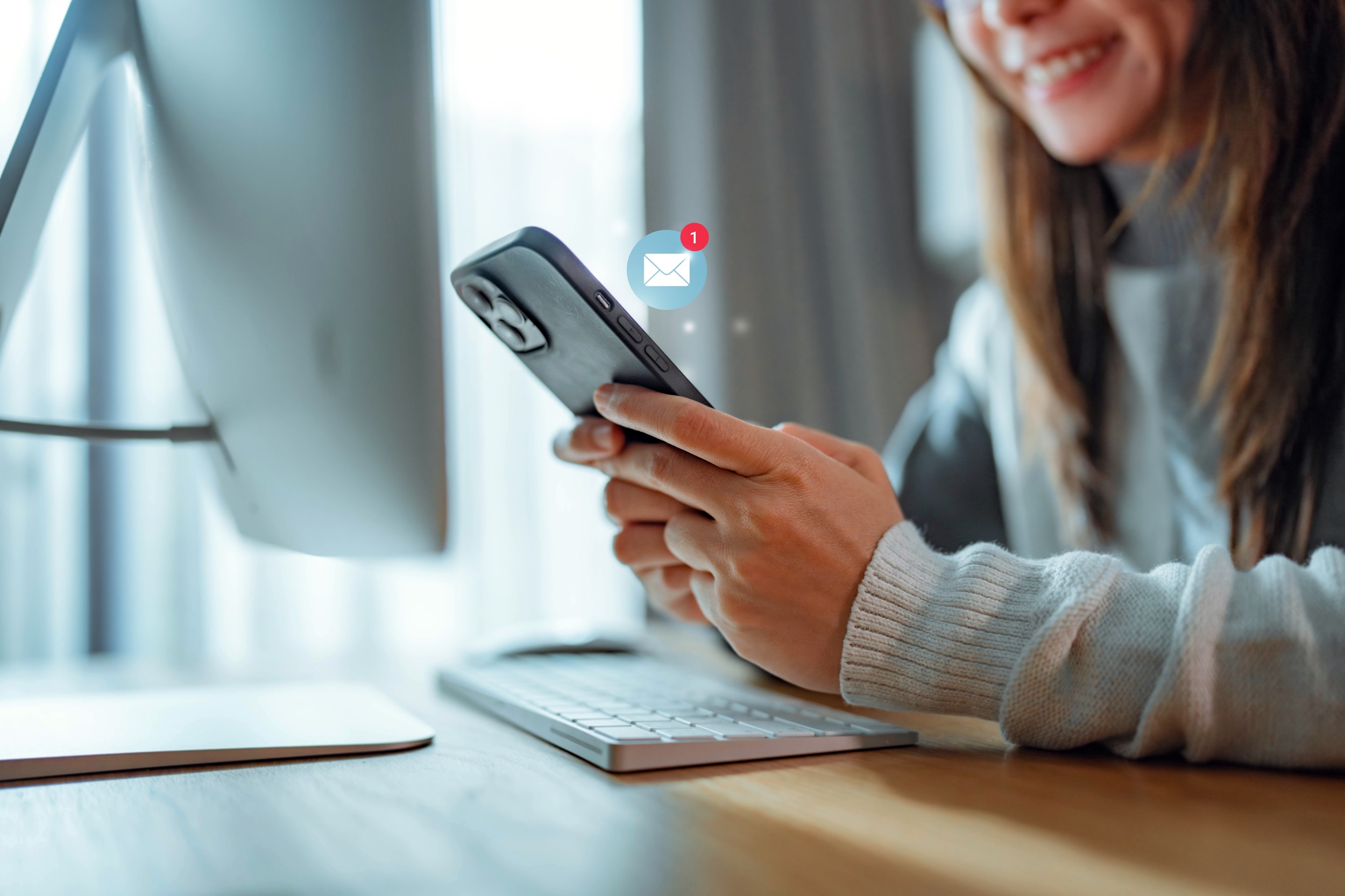 Eine Frau schaut auf ihr Handy und es erscheint ein Briefsymbol.