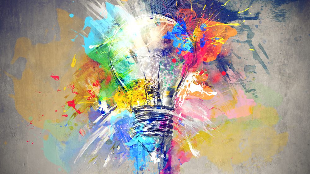 Eine leuchtende Glühbirne, umgeben von bunten Farbspritzern, symbolisiert kreative Fundraisinglösungen und innovative Ideen zur Mittelbeschaffung.